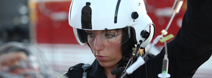 Air medical clinician in helmet monitoring IV tubing during critical care transport