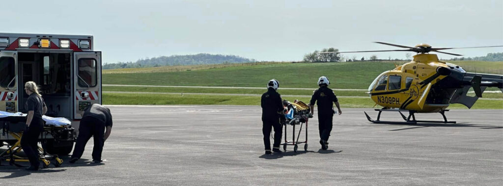 EMS crew transferring patient to PHI Air Medical helicopter on landing zone