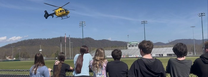 Students watching a PHI Air Medical helicopter land at their school athletic field.
