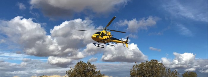 PHI Air Medical helicopter flying over desert terrain, ready for emergency transport.
