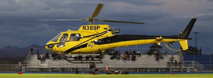 PHI Air Medical helicopter hovering over a football field before a game.