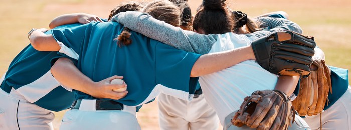 Youth sports team huddling together on the field.
