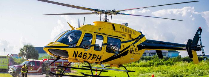 PHI Air Medical helicopter on scene with fire crews beside a rural road.