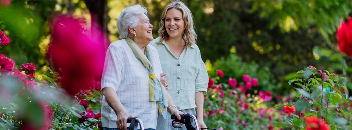 Adult daughter walking outdoors with her older mother, who is in a higher-risk group for sepsis.