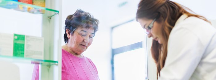 Pharmacist reviewing prescription bottles with an older adult to reduce fall risk.
