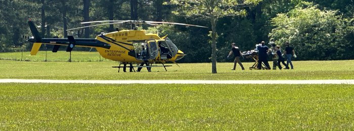 PHI Air Medical crew moving a patient to the aircraft across an open field.