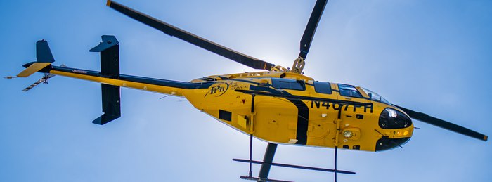 PHI Air Medical helicopter in flight in PHI yellow and black air medical aircraft livery.