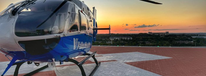 Valley Health AirCare helicopter on a rooftop helipad at sunset, a cooperative air medical program aircraft flown by PHI Air Medical crews.