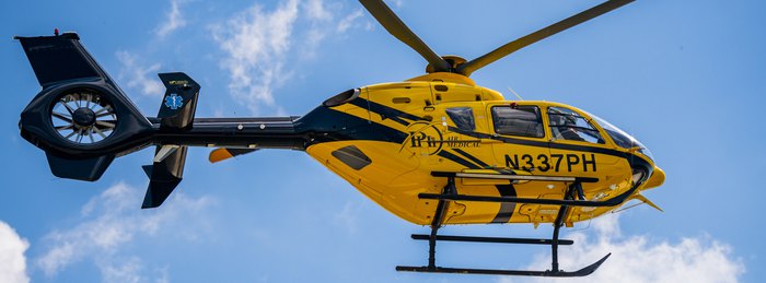 PHI Air Medical helicopter in flight, the aircraft type that responds across the membership base network.